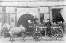 A fire carriage drawn by horses stands outside the Tampa Fire Department